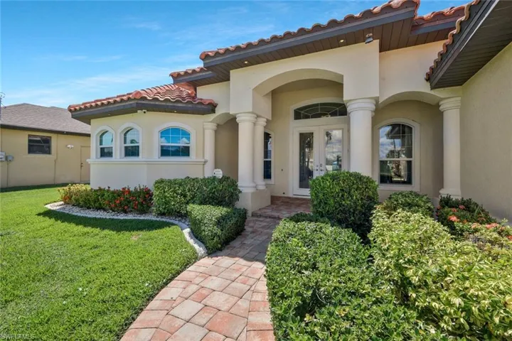 Doorway to property featuring a tile roof, stucco siding, a yard, and french doors