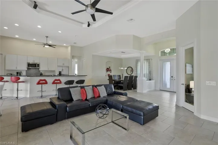 Living area featuring a tray ceiling, ceiling fan, a towering ceiling, recessed lighting, and decorative columns