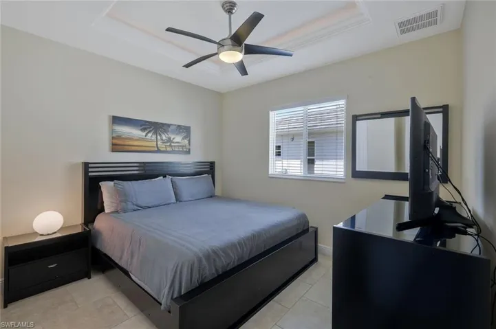 Bedroom featuring a tray ceiling, a ceiling fan, and light tile patterned floors