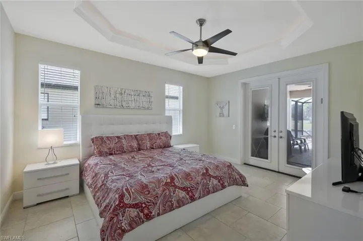 Bedroom with a tray ceiling, french doors, and multiple windows