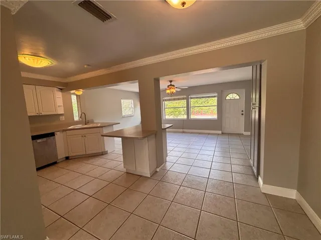 The property features an open-concept living space with tile flooring, white kitchen cabinetry, and a stainless steel appliances