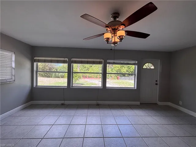 This living space features tiled flooring, a ceiling fan with integrated lighting, and multiple windows providing natural light