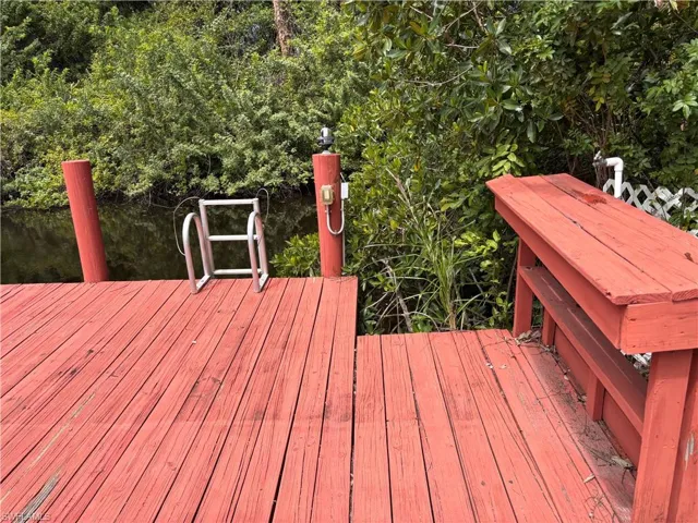 The property features a red wooden deck with a built-in bench, two red wooden posts, and a white ladder leading into the water