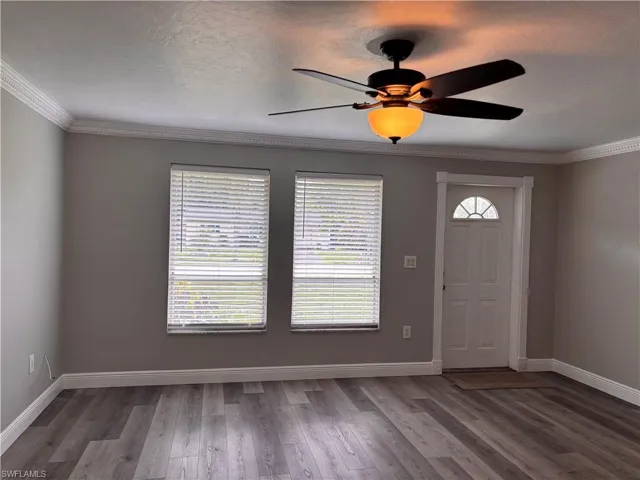 This entry space features gray walls, a white front door with an arched glass insert, and two windows with blinds