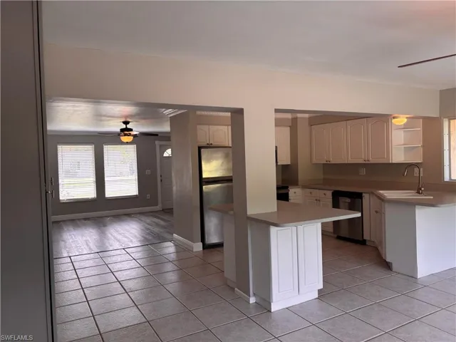 The property features a kitchen with white cabinetry, a stainless steel refrigerator, and a sink with a gooseneck faucet