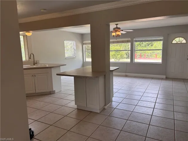 The property features tile flooring throughout, a kitchen area with light-colored cabinetry, a sink with a faucet, and a countertop