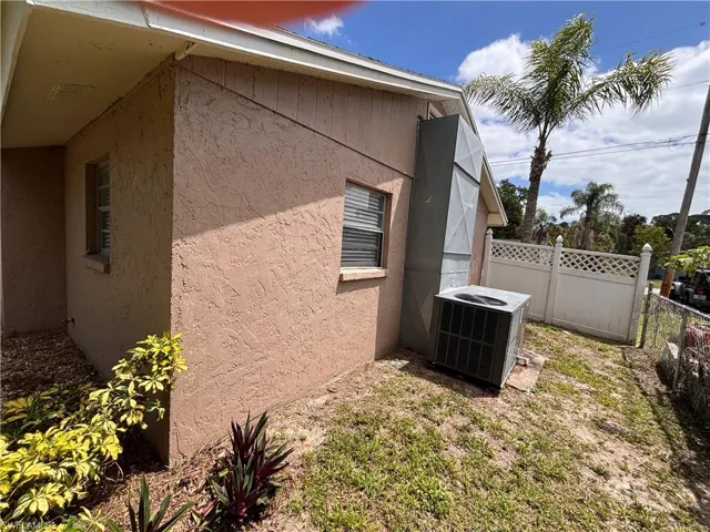 Exterior of the property featuring stucco siding, a window with blinds, and a white fence