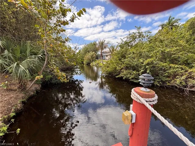Scenic waterway with lush green foliage along its banks and a partial view of a property in the distance