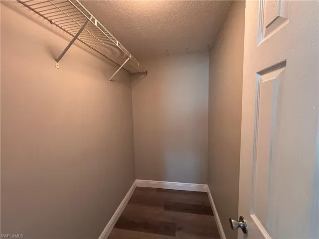 This closet features wire shelving, wood-style flooring, and a white interior door with a silver knob