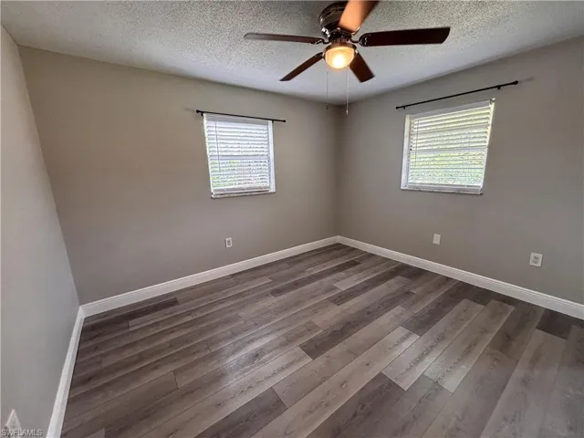 This inviting room features wood-look flooring, neutral wall paint, and a ceiling fan with an integrated light fixture