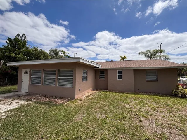 The property features an exterior with a tan finish, a brown shingle roof, and a white entry door
