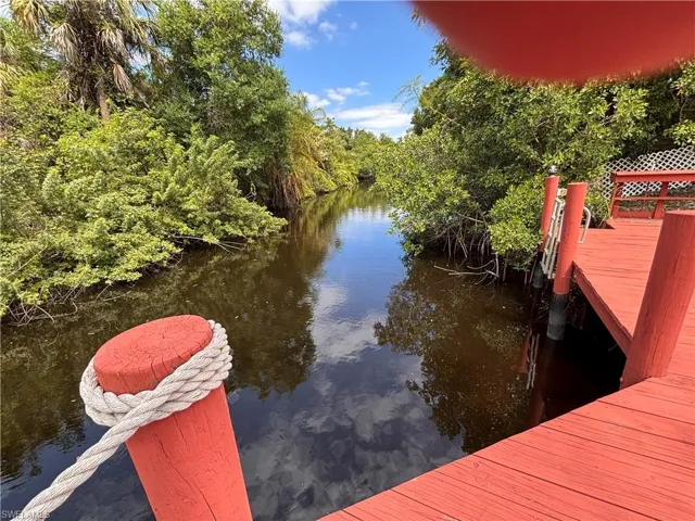 The property features a private dock with vibrant red decking, offering direct access to the waterway