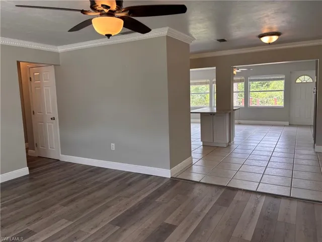 This property features a spacious room with wood-look flooring and crown molding