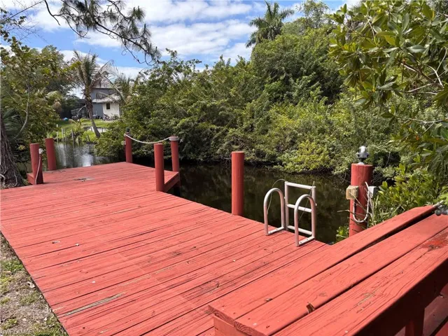 The property features a red wooden dock with a rope railing, providing direct access to the canal