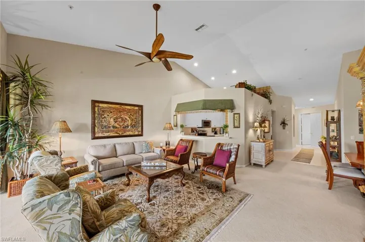 Living area with light carpet, a ceiling fan, recessed lighting, and vaulted ceiling