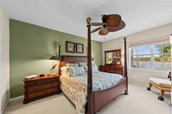 Bedroom featuring light carpet, a ceiling fan, and a water view