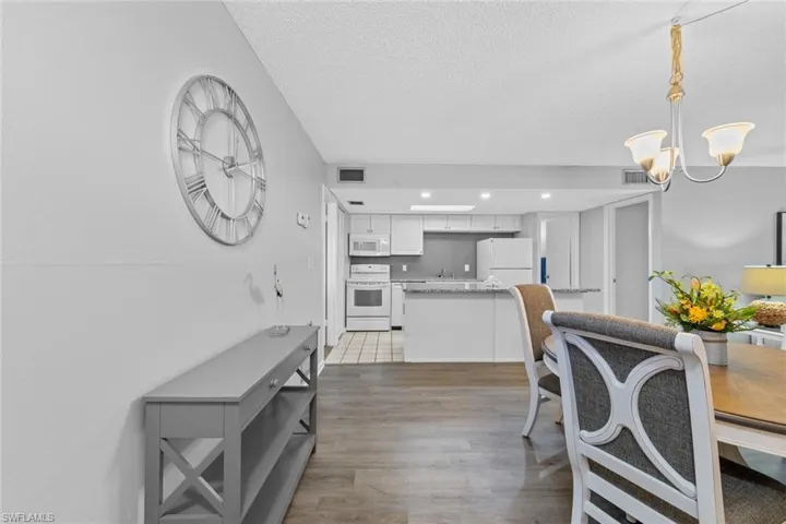 Dining room with hardwood / wood-style flooring, a textured ceiling, and an inviting chandelier
