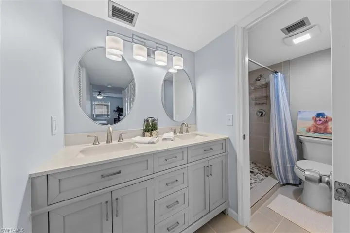 Bathroom with toilet, vanity, tile patterned floors, and curtained shower