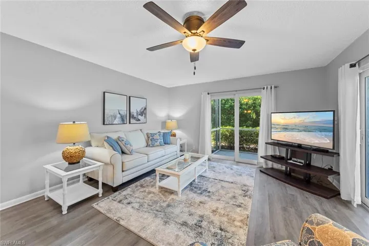 Living room featuring a textured ceiling, wood-type flooring, and ceiling fan