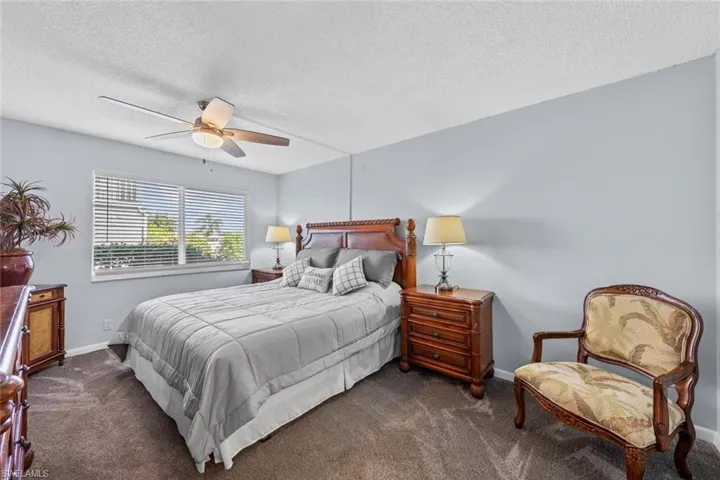 Carpeted bedroom with a textured ceiling and ceiling fan