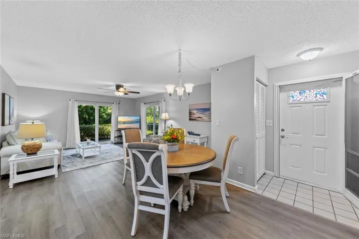 Dining room featuring ceiling fan with notable chandelier, a textured ceiling, and light hardwood / wood-style flooring