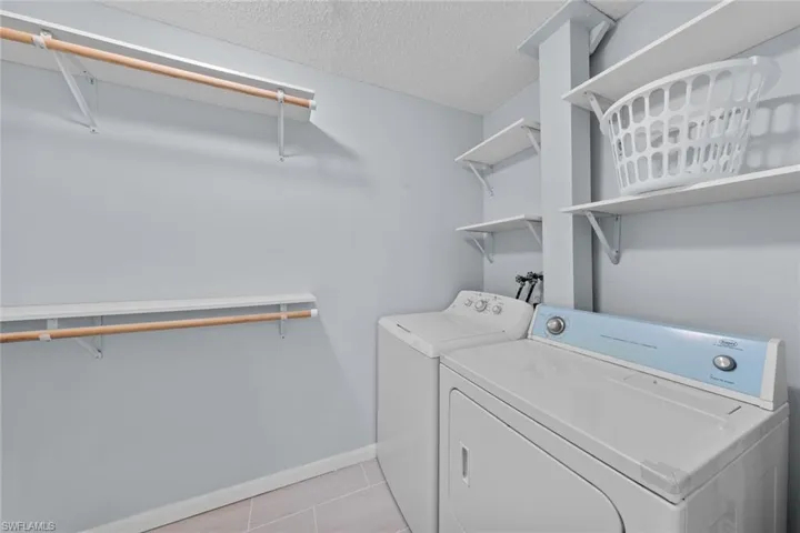 Clothes washing area featuring washer and dryer, and light tile patterned floors