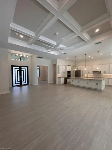 Unfurnished living room featuring coffered ceiling, recessed lighting, beamed ceiling, wine cooler, and dark wood-type flooring