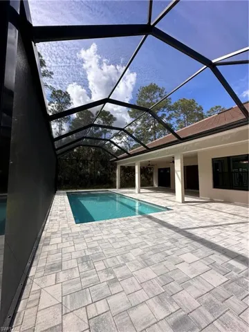 Swimming pool featuring a sunroom, glass enclosure, and a patio area