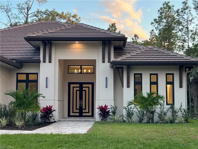 View of exterior entry featuring a lawn, stucco siding, and a tiled roof