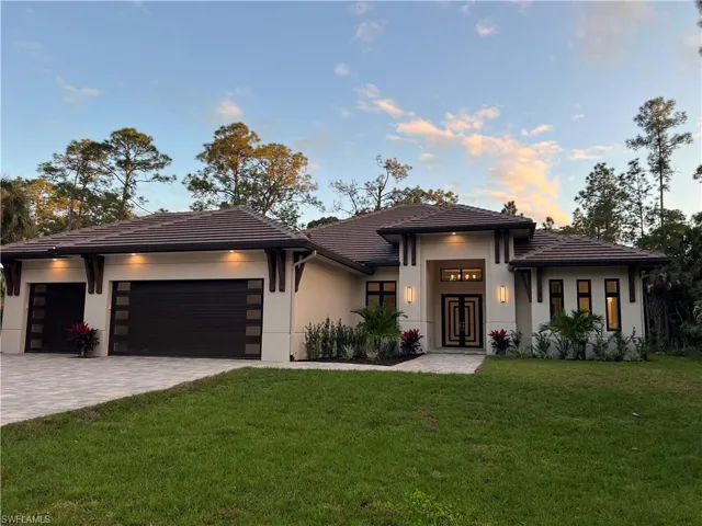 Prairie-style house featuring a front lawn, a garage, decorative driveway, and stucco siding