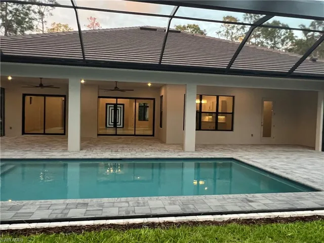 Rear view of house with a patio area, an outdoor pool, glass enclosure, and ceiling fan