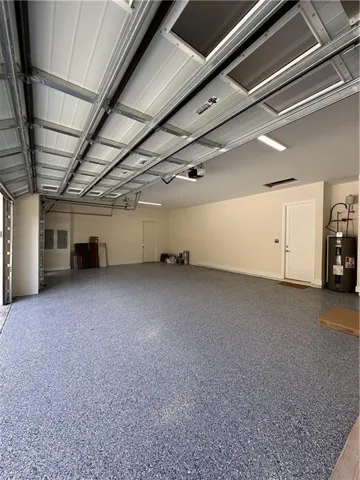 Misc room with a garage, speckle patterned floor, water heater, and electric panel