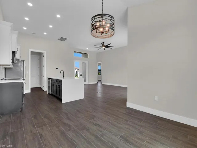 Empty room featuring wood tiled floors, hanging lights, and vaulted ceiling