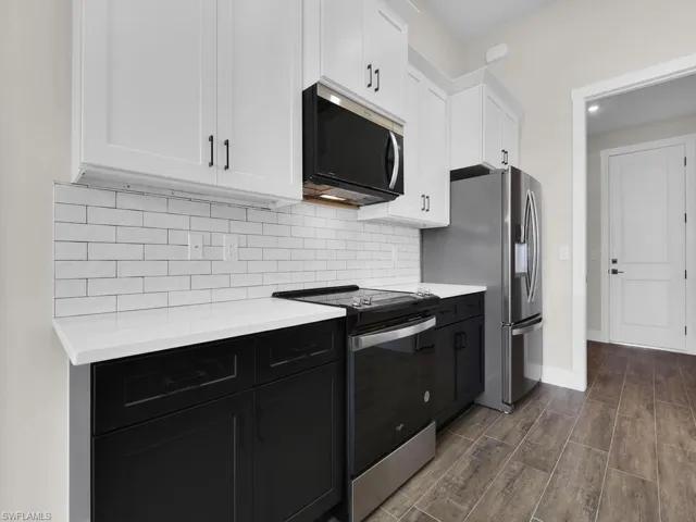 Kitchen featuring light stone counters, wood tiled floors, ceiling fan, a large fireplace, and open floor plan