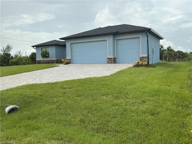 Prairie-style home with stone siding, stucco siding, a lawn, decorative driveway, and an attached garage
