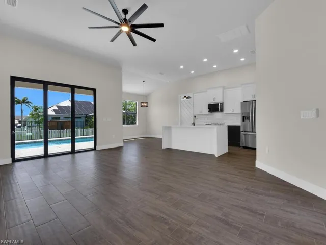 Unfurnished living room featuring a glass covered fireplace, ceiling fan, wood finish floors, and an accent wall