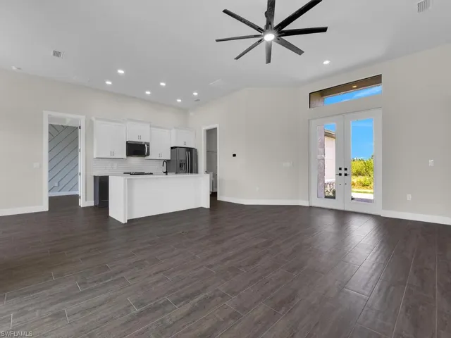 Bedroom featuring an accent wall, a tray ceiling, wood finished floors, ceiling fan, and wooden walls