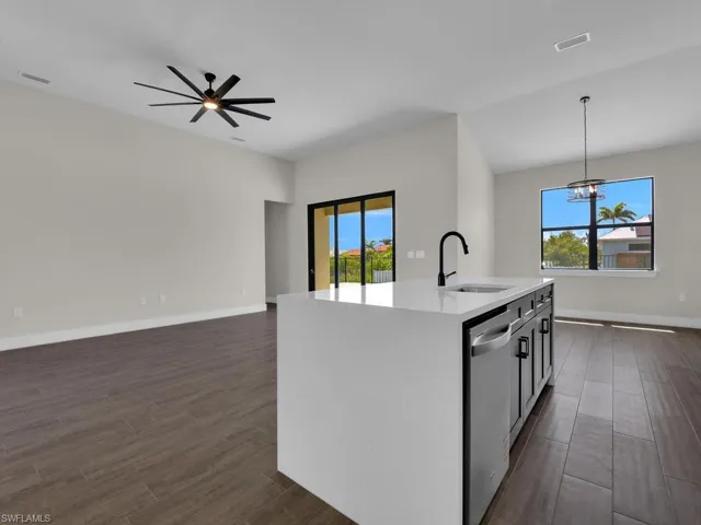 Kitchen featuring light stone counters, an island with sink, wood finish floors, tasteful backsplash, and stainless steel appliances