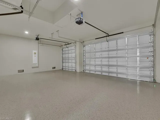 Garage featuring electric panel, a garage door opener, and recessed lighting