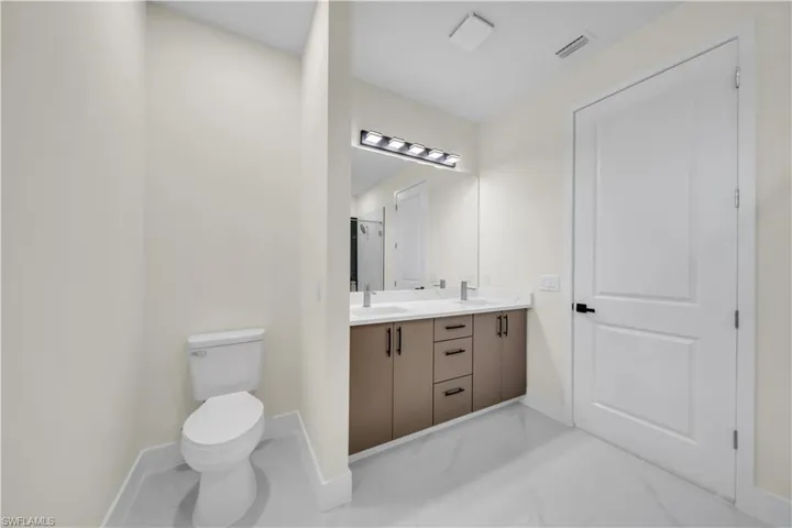 Full bathroom with double vanity and marble look tiles