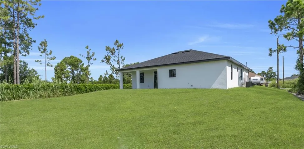 Rear view of house featuring stucco siding and a yard
