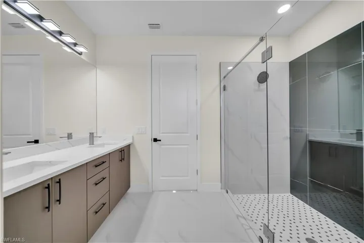 Bathroom featuring a marble finish shower and double vanity