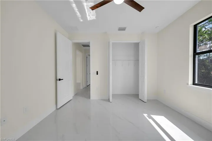 Unfurnished bedroom featuring light marble finish floors, a closet, and a ceiling fan