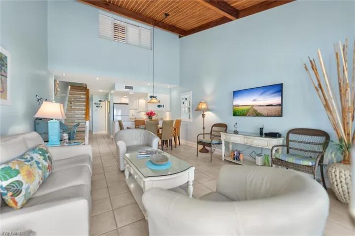 Living room featuring light tile patterned flooring and a high wood beamed ceiling