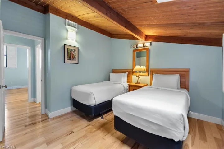 Bedroom with a wood ceiling with exposed beams and light wood-style flooring