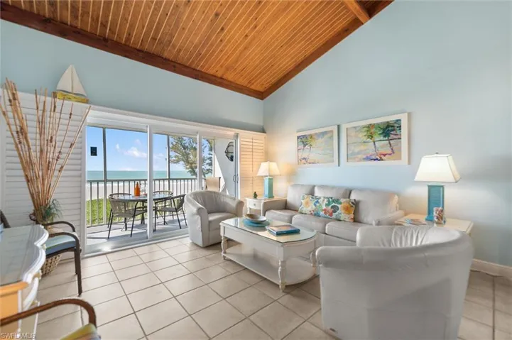 Living room with a high wooden beamed ceiling, a water view, and light tile patterned floors