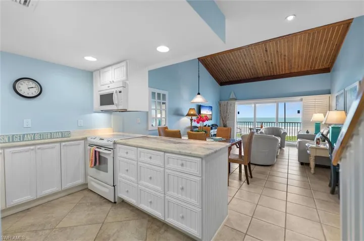 Kitchen with white appliances, a peninsula, pendant lighting, open floor plan, and light tile patterned floors