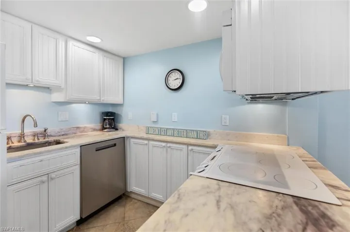 Kitchen featuring white appliances, white cabinetry, light stone counters, and light tile patterned floors