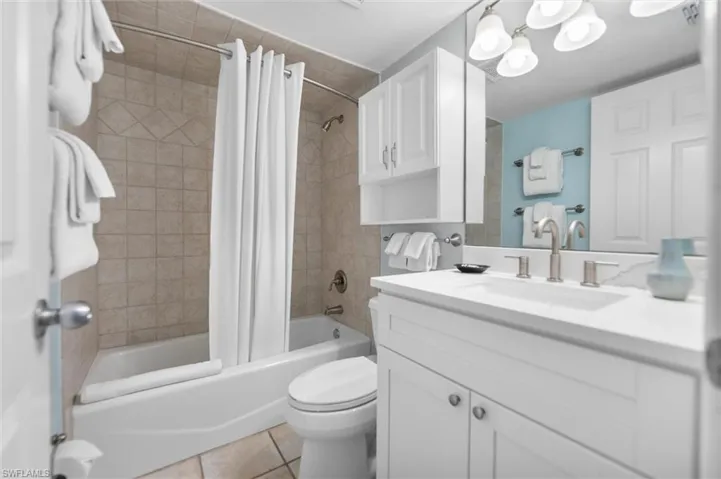 Bathroom with vanity, shower / bath combo with shower curtain, and light tile patterned floors