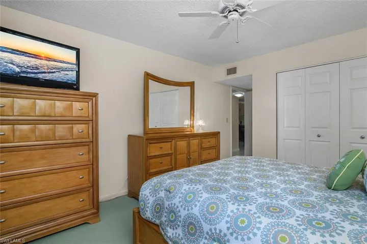 Carpeted bedroom featuring a closet, a textured ceiling, and a ceiling fan
